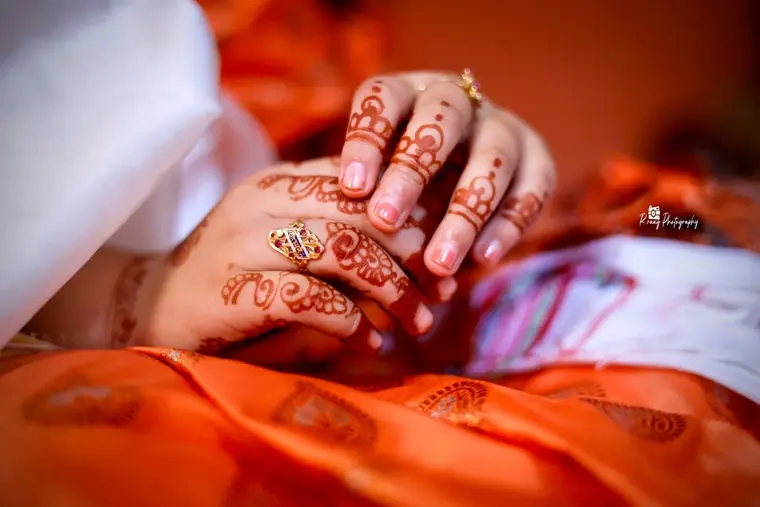 Mehendi hands resting on orange silk